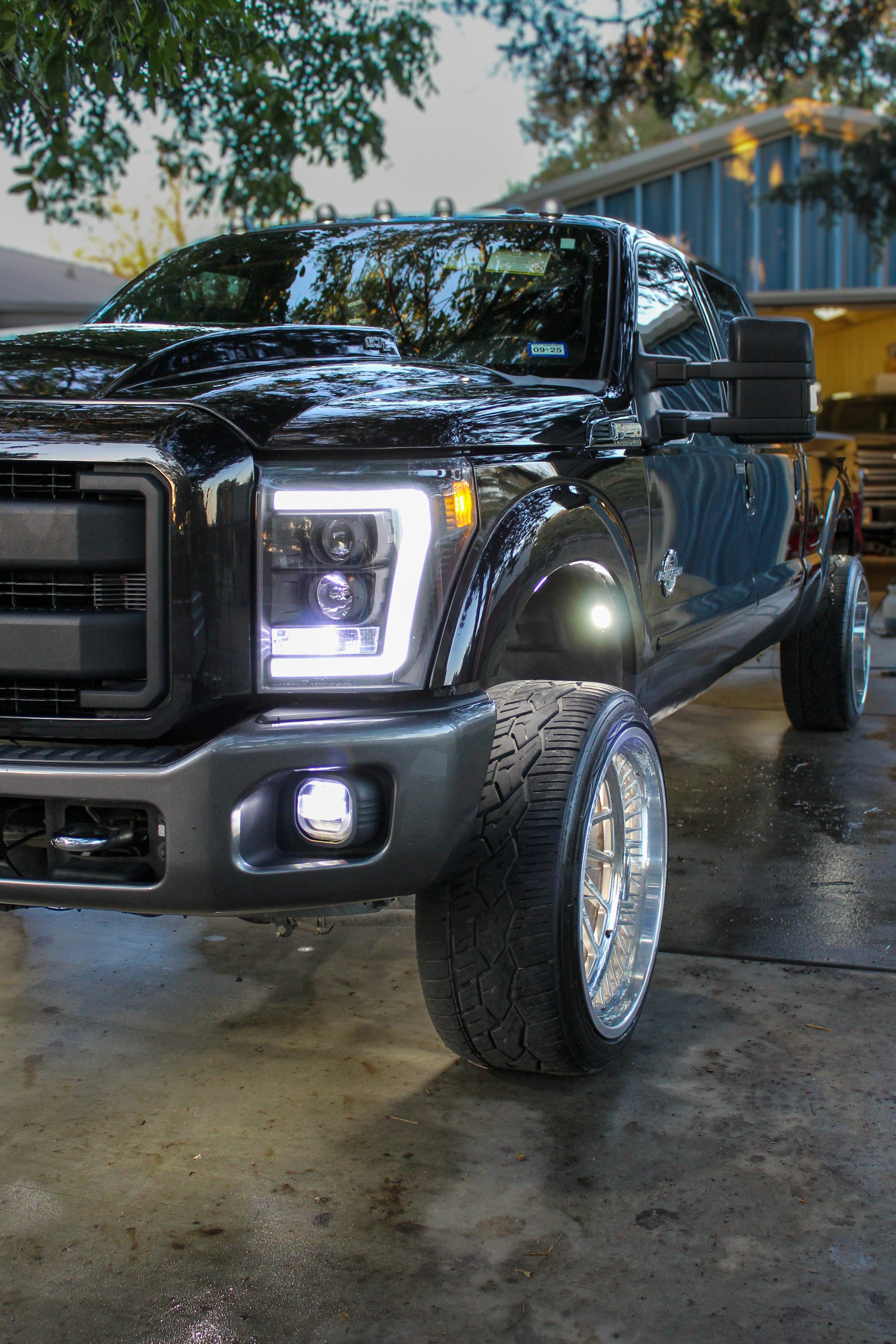 Front corner of a lifted black Ford F-250 with custom LED headlights, built by 2 Man Fab