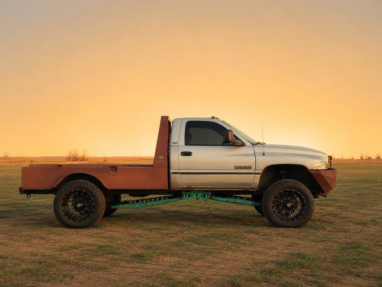 Second-gen Dodge Ram 2500 with a custom raw steel flatbed and traction bars, built by 2 Man Fab