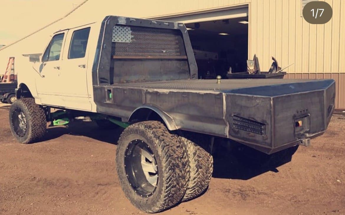 White crew-cab dually with a custom steel flatbed and American flag headache rack, built by 2 Man Fab